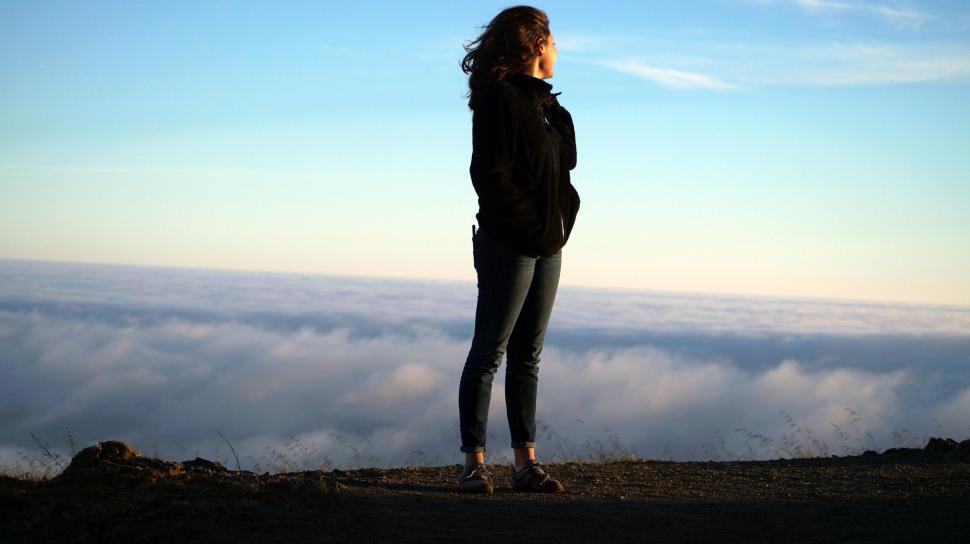 Free Image of Woman Standing on Top of Mountain Overlooking Clouds 