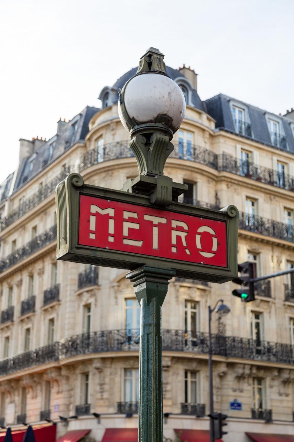 Free Image of Red Metro Sign in Front of Tall Building 