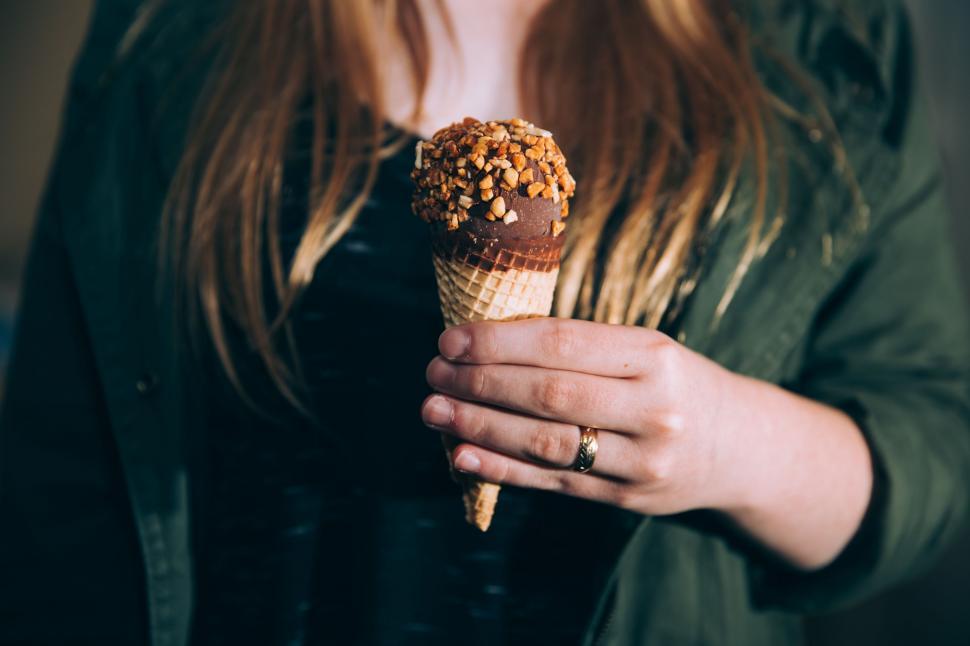Free Image of Woman Holding Ice Cream Cone With Nuts 