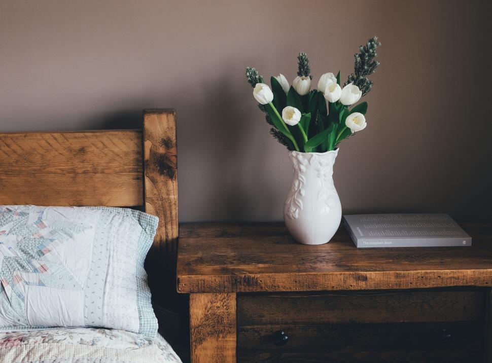 Free Image of Wooden Headboard Bed With White Vase and Flowers 