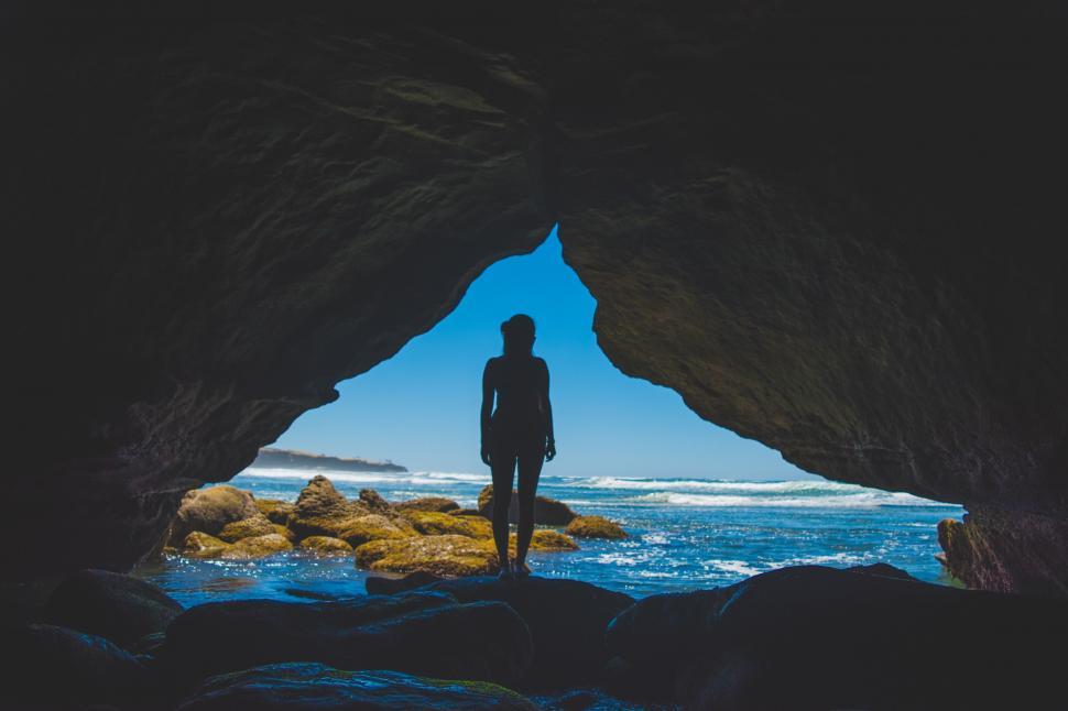 Free Image of Person Standing in Cave Looking Out at Ocean 