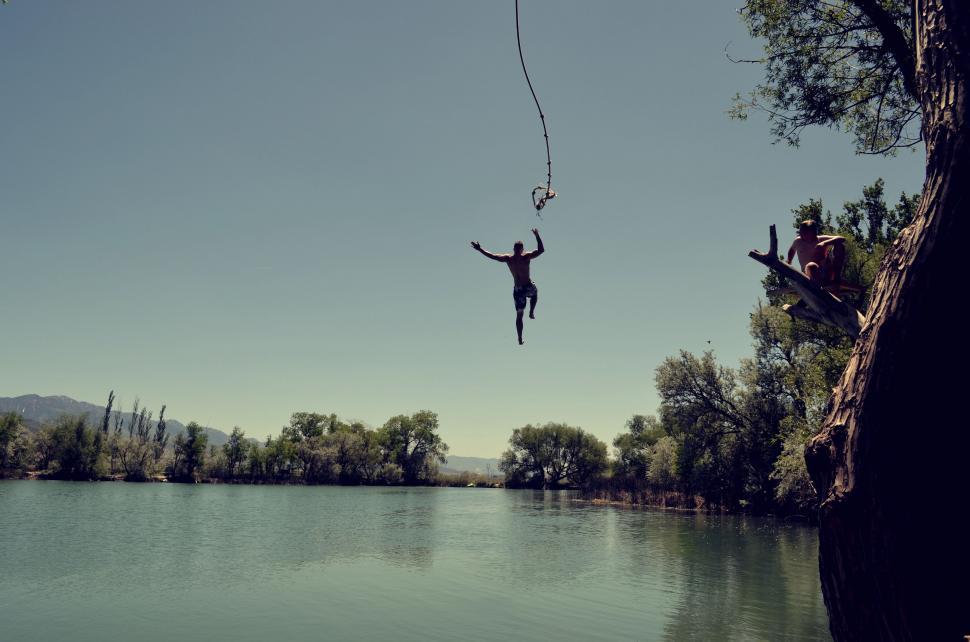 Free Image of Person Hanging From Rope Over Body of Water 