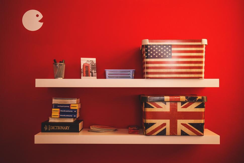 Free Image of Red Wall With White Shelf, Books, and Flag 