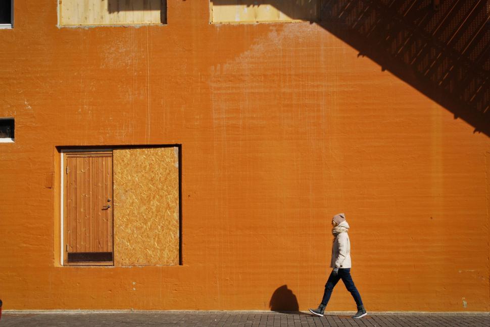 Free Image of Person Walking Down Street Past Building 