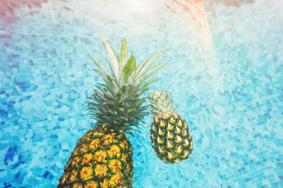 Free Image of Two Pineapples Floating in a Pool of Water 