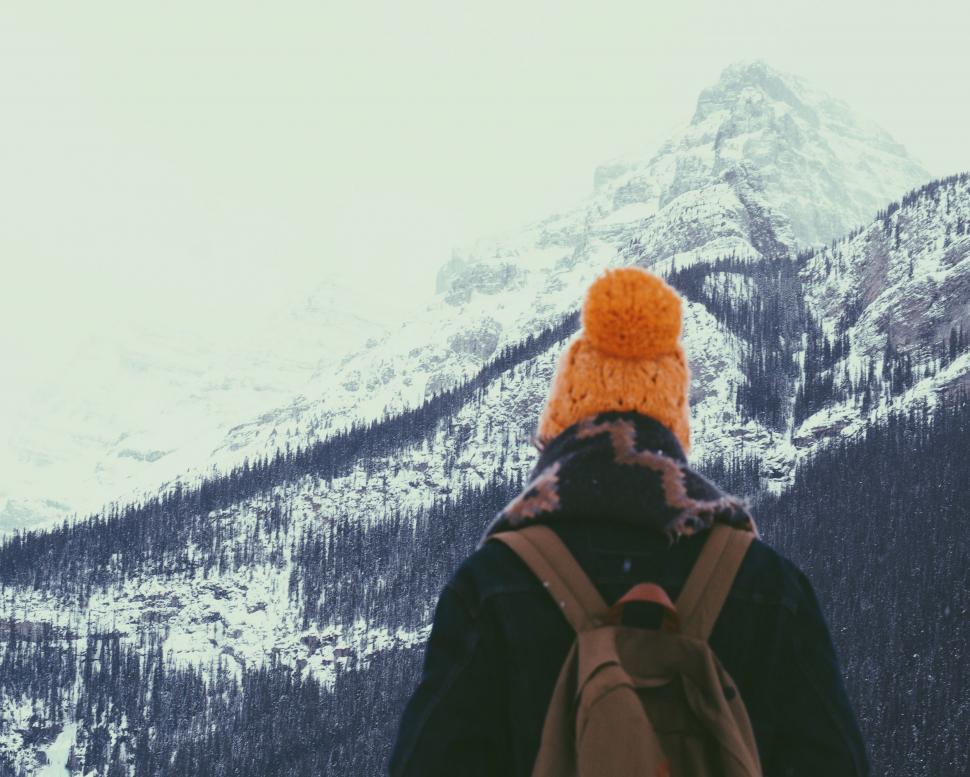 Free Image of Person With Backpack and Hat Standing in Front of Mountain 