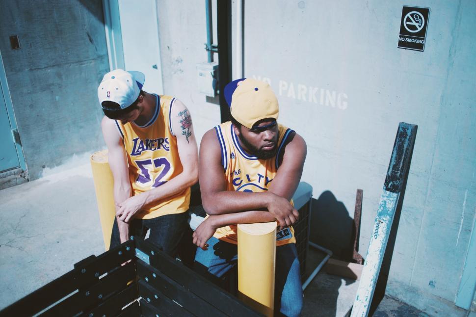 Free Image of Two Basketball Players Sitting on a Bench With Crossed Arms 
