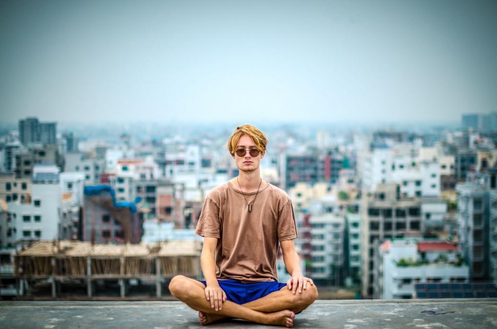 Free Image of Man Sitting in Yoga Pose in Front of Cityscape 