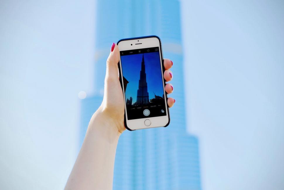 Free Image of Person Holding Up Cell Phone in Front of Building 