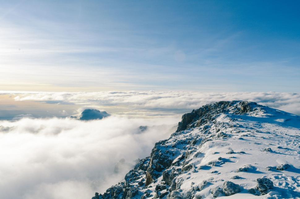 Free Image of Majestic Mountain Covered in Snow and Clouds Under Blue Sky 