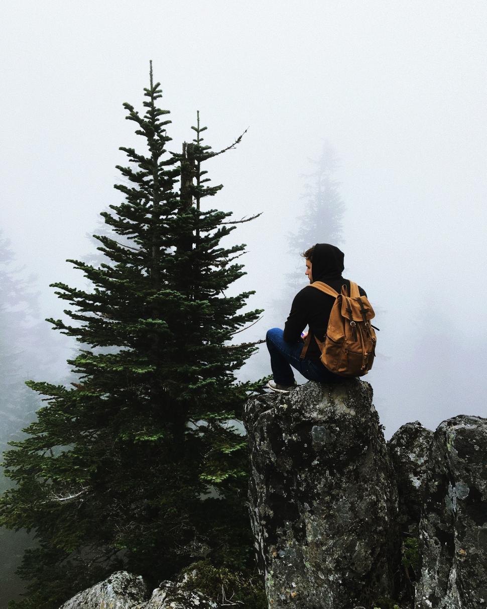 Free Image of Man Sitting on Top of a Mountain With a Backpack 