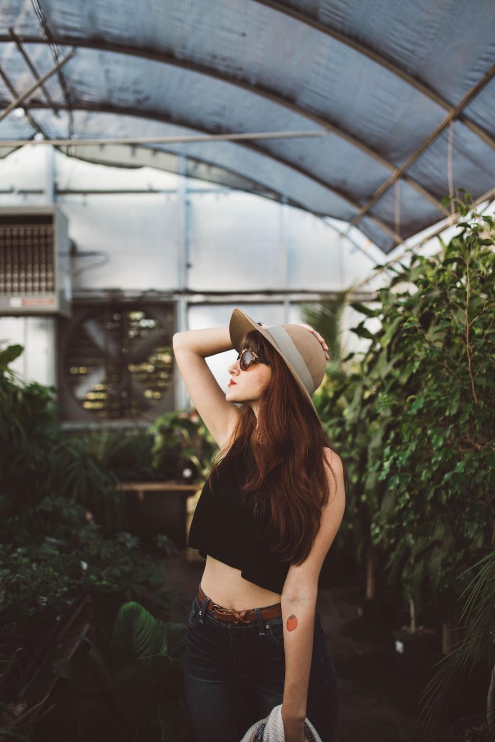 Free Image of Woman Standing in Greenhouse With Hat 