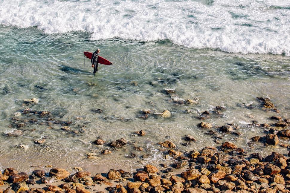 Free Image of Man Holding Surfboard Standing in Ocean 