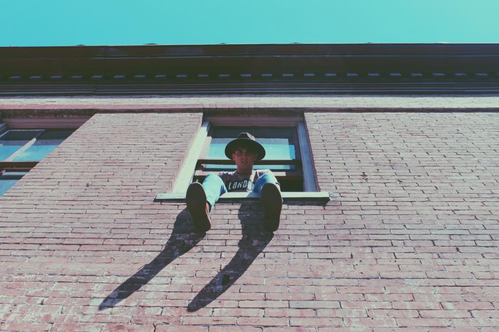 Free Image of Person Standing in Window of Brick Building 