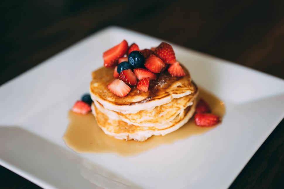 Free Image of Stack of Pancakes Topped With Strawberries and Syrup 