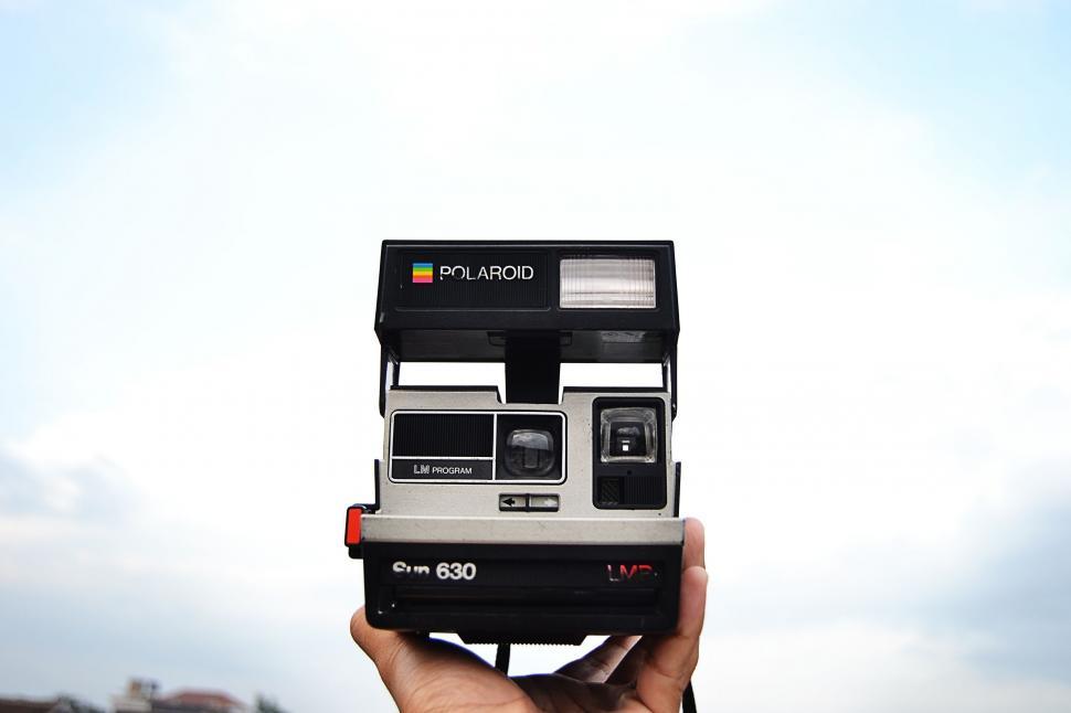 Free Image of Person Holding Polaroid Camera Up to Sky 