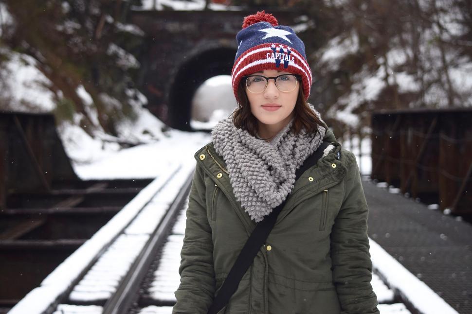 Free Image of Woman Standing on Snow-Covered Train Tracks 