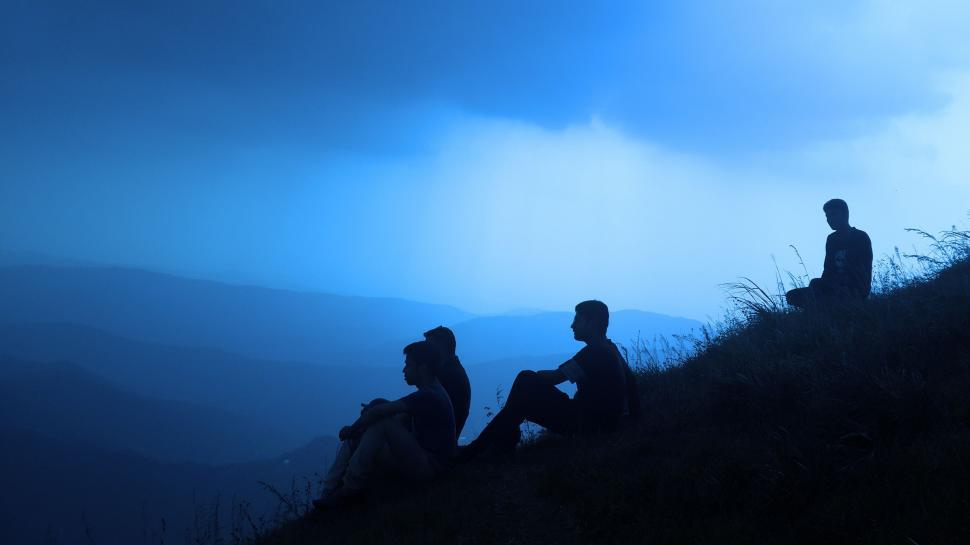 Free Image of Three People Sitting on a Hill in the Dark 