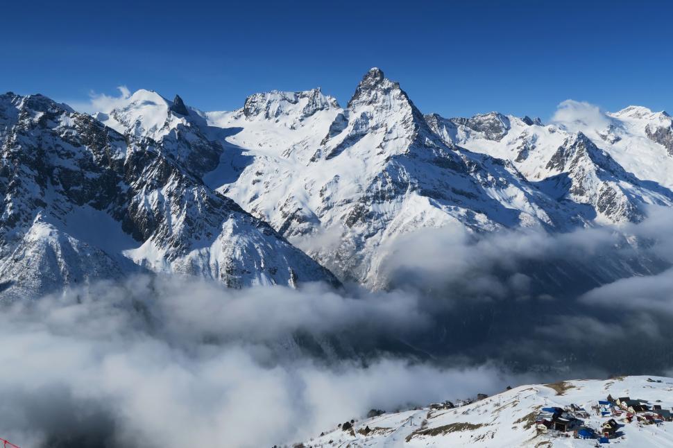 Free Image of Majestic Mountain Range Covered in Snow and Clouds 