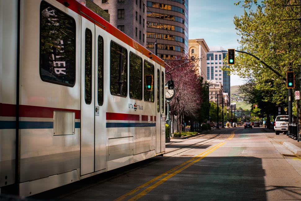 Free Image of Train Traveling Down Street Next to Tall Buildings 