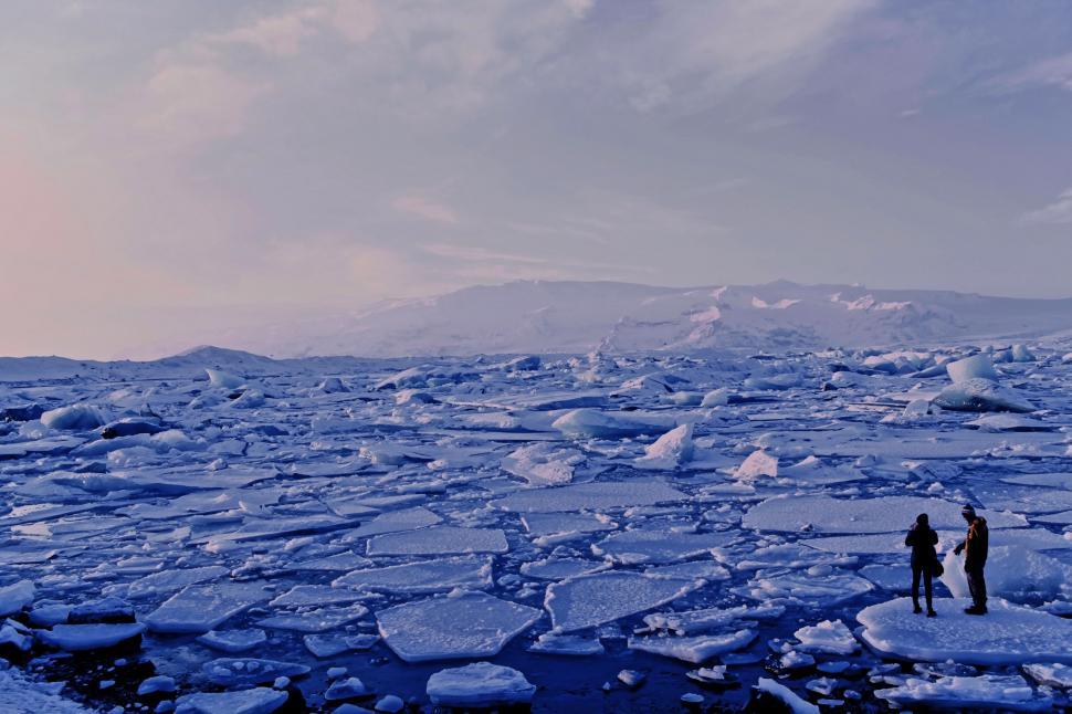Free Image of Two People Standing on Ice Floes in the Middle of the Ocean 
