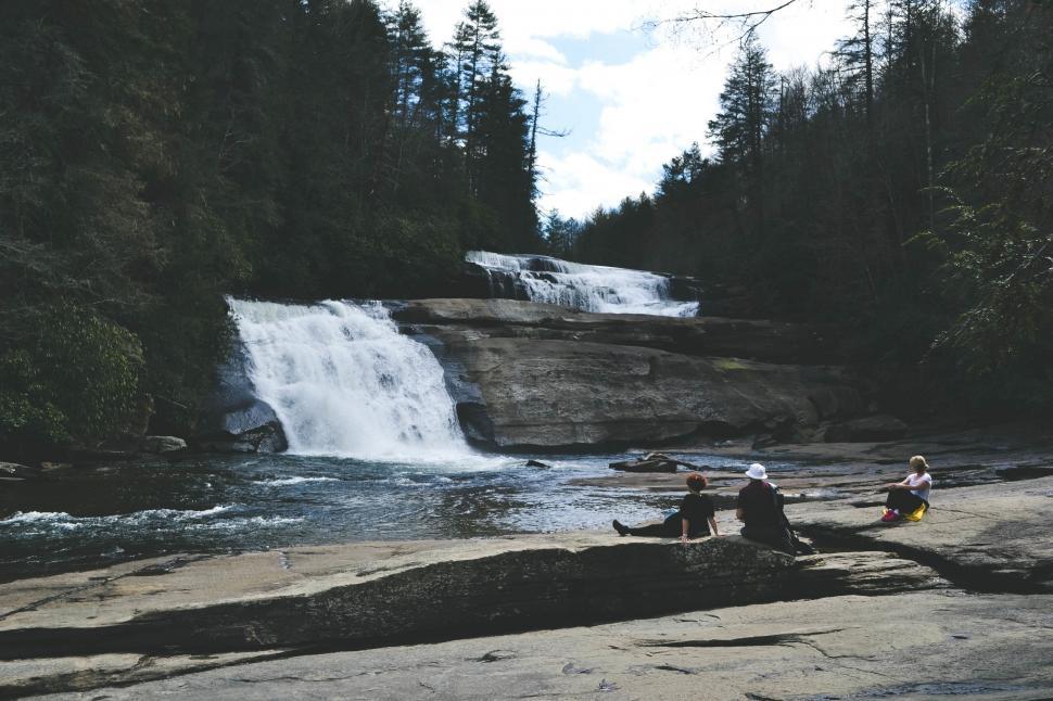 Free Image of Group of People Sitting on Top of Rock Next to Waterfall 