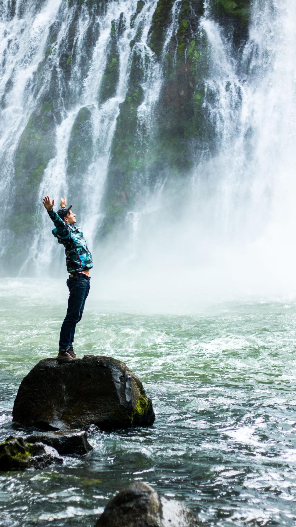 Free Image of Person Standing on Rock in Front of Waterfall 