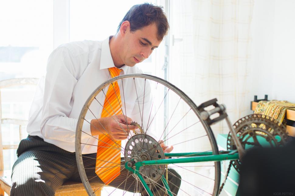 Free Image of A Man Working on Fixing a Bicycle Wheel in a Room 
