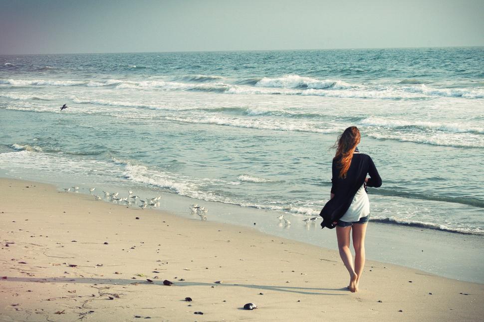 Free Image of Woman Walking Along Beach by the Ocean 