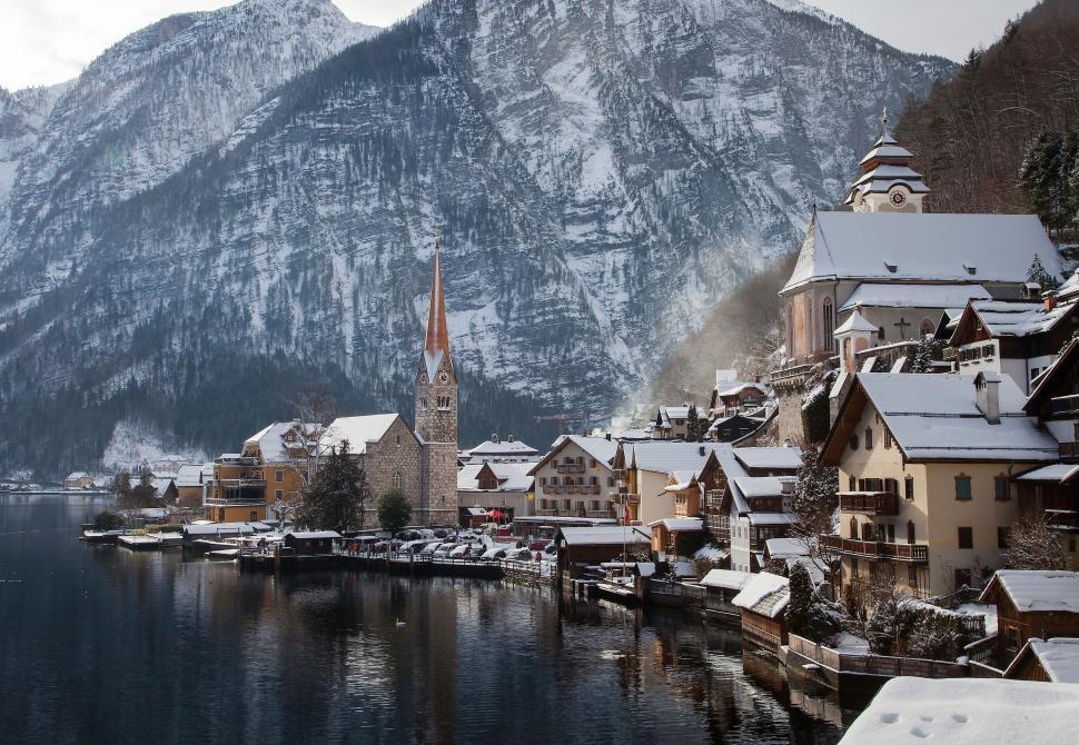 Free Image of Snowy Village on Lake With Mountains in Background 