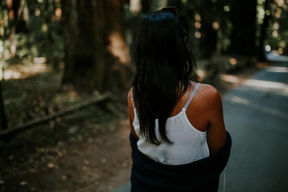 Free Image of Woman Walking Down Street Next to Forest 
