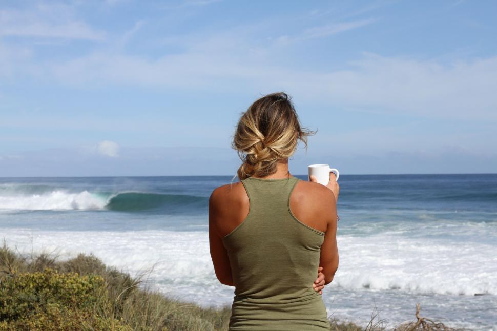 Free Image of Woman Sitting on Hill Looking at Ocean 