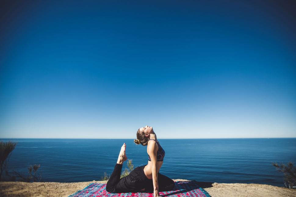 Free Image of Woman Performing Yoga on Blanket by Ocean 