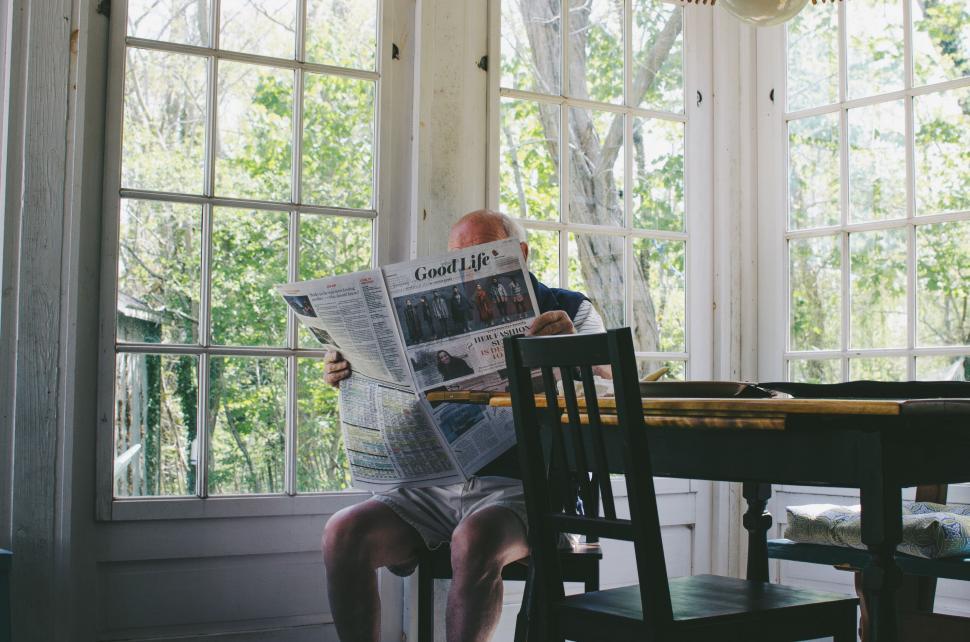 Free Image of Person Reading Newspaper at Table 