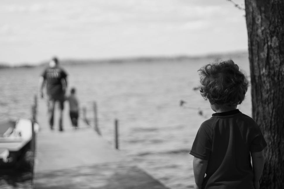 Free Image of Young Boy Standing on Dock by Water 