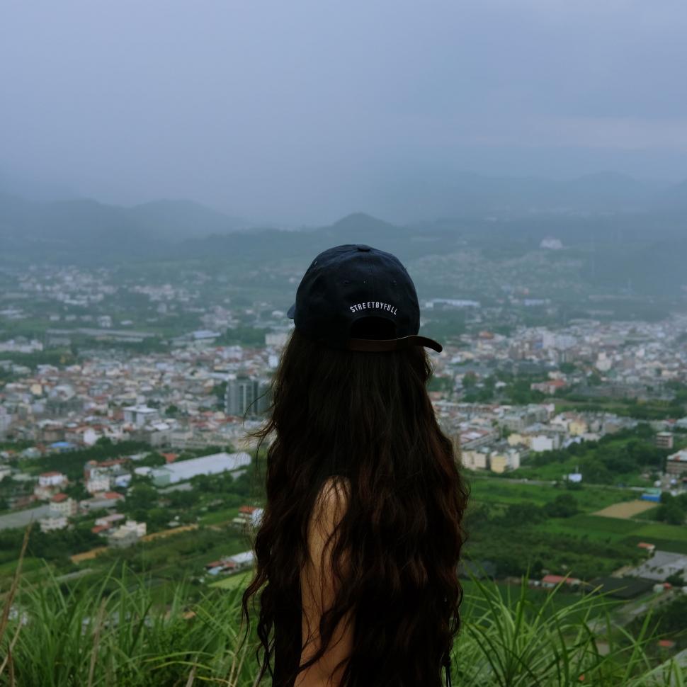 Free Image of Woman With Long Hair Wearing Hat Looking Out Over City 