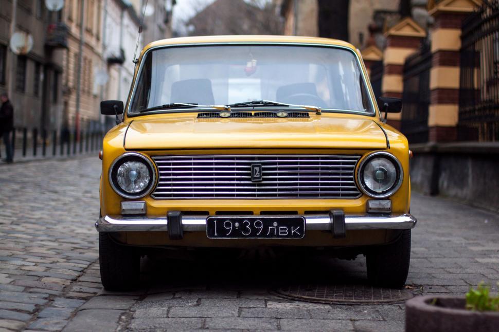 Free Image of Yellow Car Parked on Cobblestone Street 