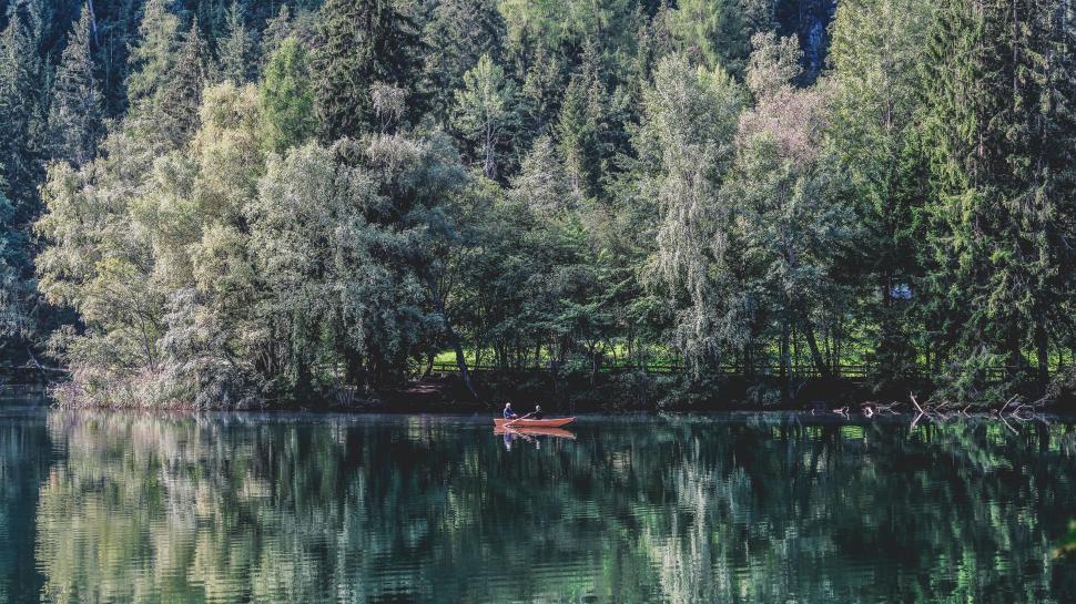 Free Image of Small Boat Floating on Lake Surrounded by Trees 