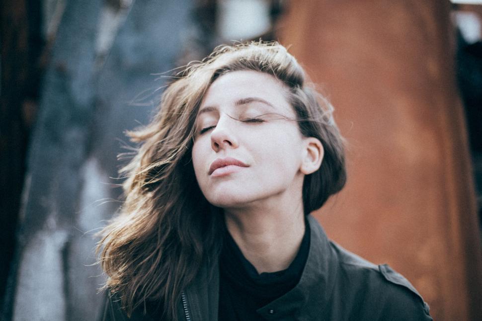 Free Image of Woman With Eyes Closed and Hair Blowing in the Wind 