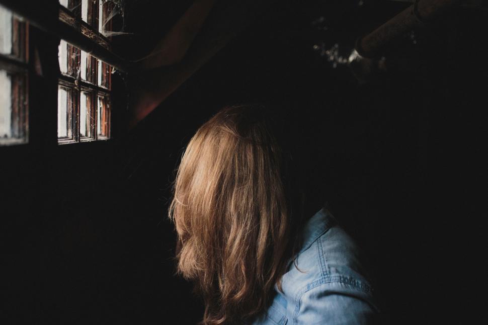 Free Image of Woman Looking Out of Window in Dark Room 