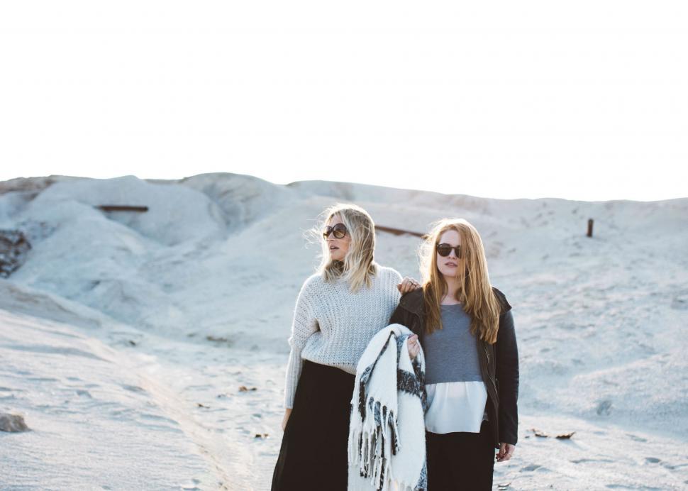 Free Image of Two Women Standing in Snow Holding Surfboard 