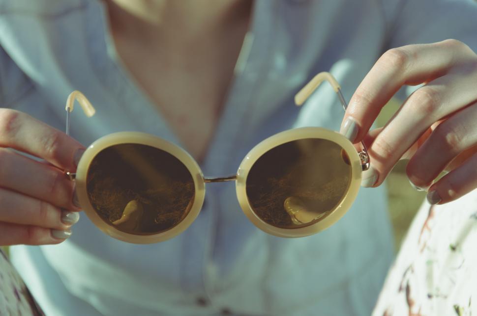 Free Image of A Woman Holding a Pair of Round Glasses 