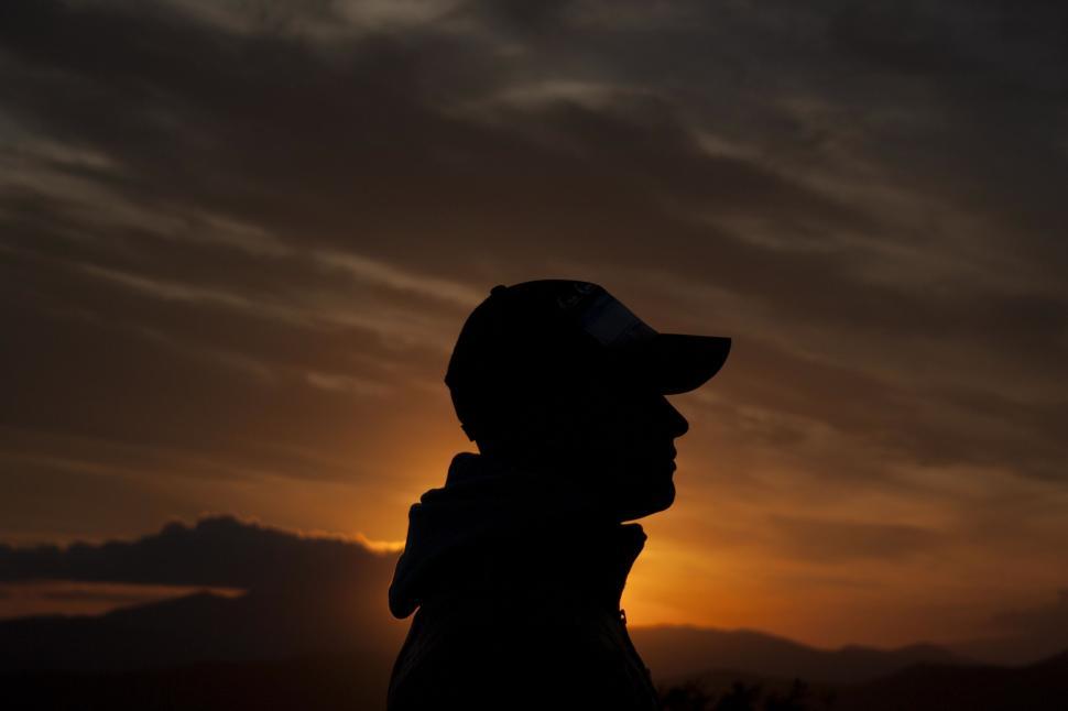 Free Image of Person in Hat Silhouetted Against Sunset 