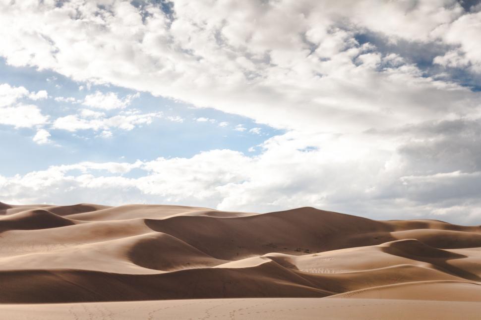 Free Image of Vast Sand Dunes Beneath Cloudy Sky 