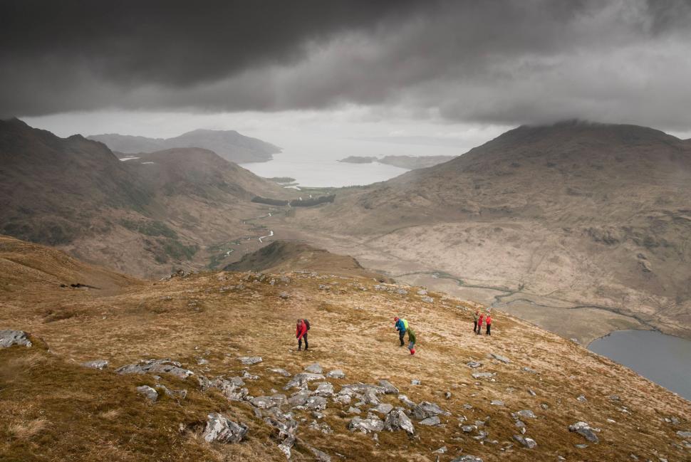 Free Image of Group of People Walking Up a Hill on Cloudy Day 