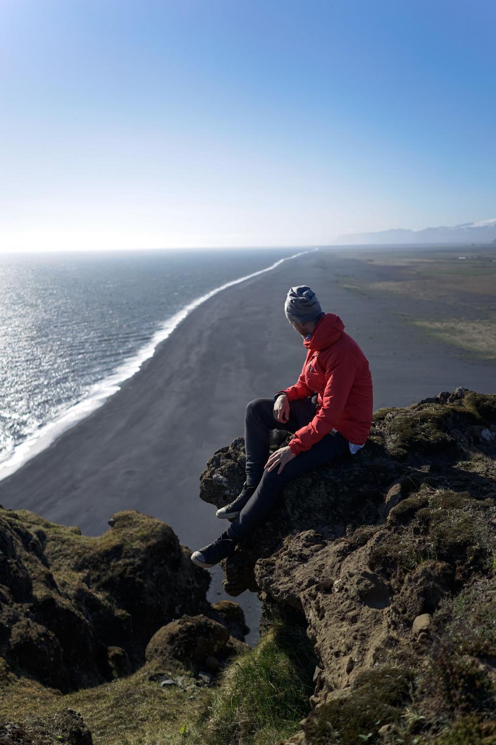 Free Image of Man in Red Jacket Sitting on Rock 