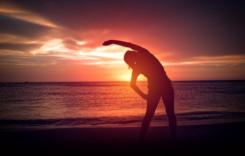 Free Image of Silhouette of Young Woman - Warm-Up exercise on the Beach at Sun 