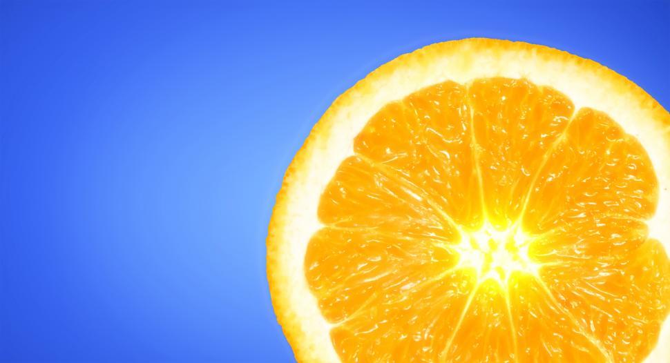 Free Image of Orange Slice on Sky Blue Background - Vivid Colors with Copyspac 