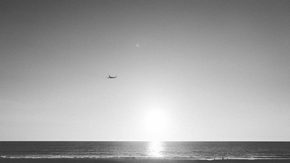 Free Image of Plane Flying Over Ocean on Sunny Day 