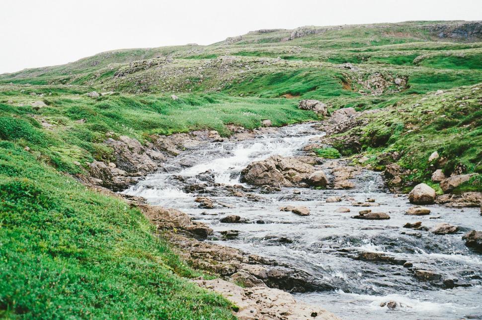 Free Image of Stream Flowing Through Lush Green Hillside 